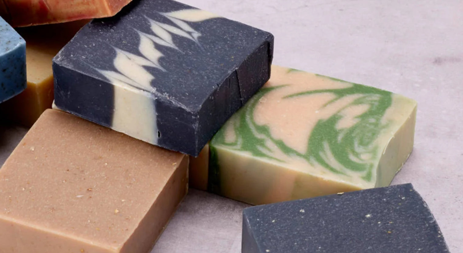 Assorted bars of soap with different colors and patterns on a light gray background