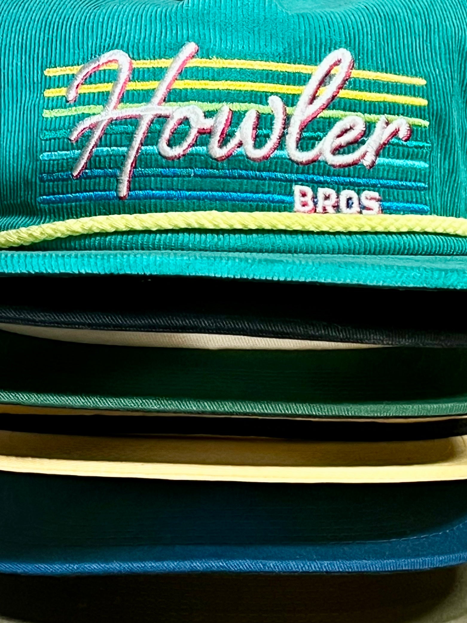 Stacks of hats in different colors close up showing one with a Howler Bros. logo
